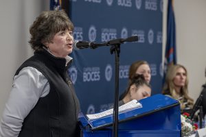 a woman addresses a crowd using a microphone