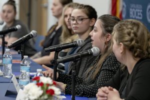 several young women sit at a table as part of a panel