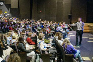 a man speaks to an auditorium filled with students