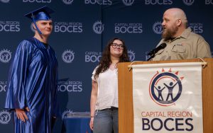 a young man in a graduation cap and gown is recognized up on a stage