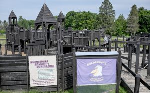 a wooden playground with a sign 