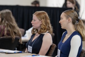 two young teen girls sit at a table listening to a presentation