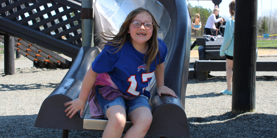 a young girl smiles as she finishes using the slide