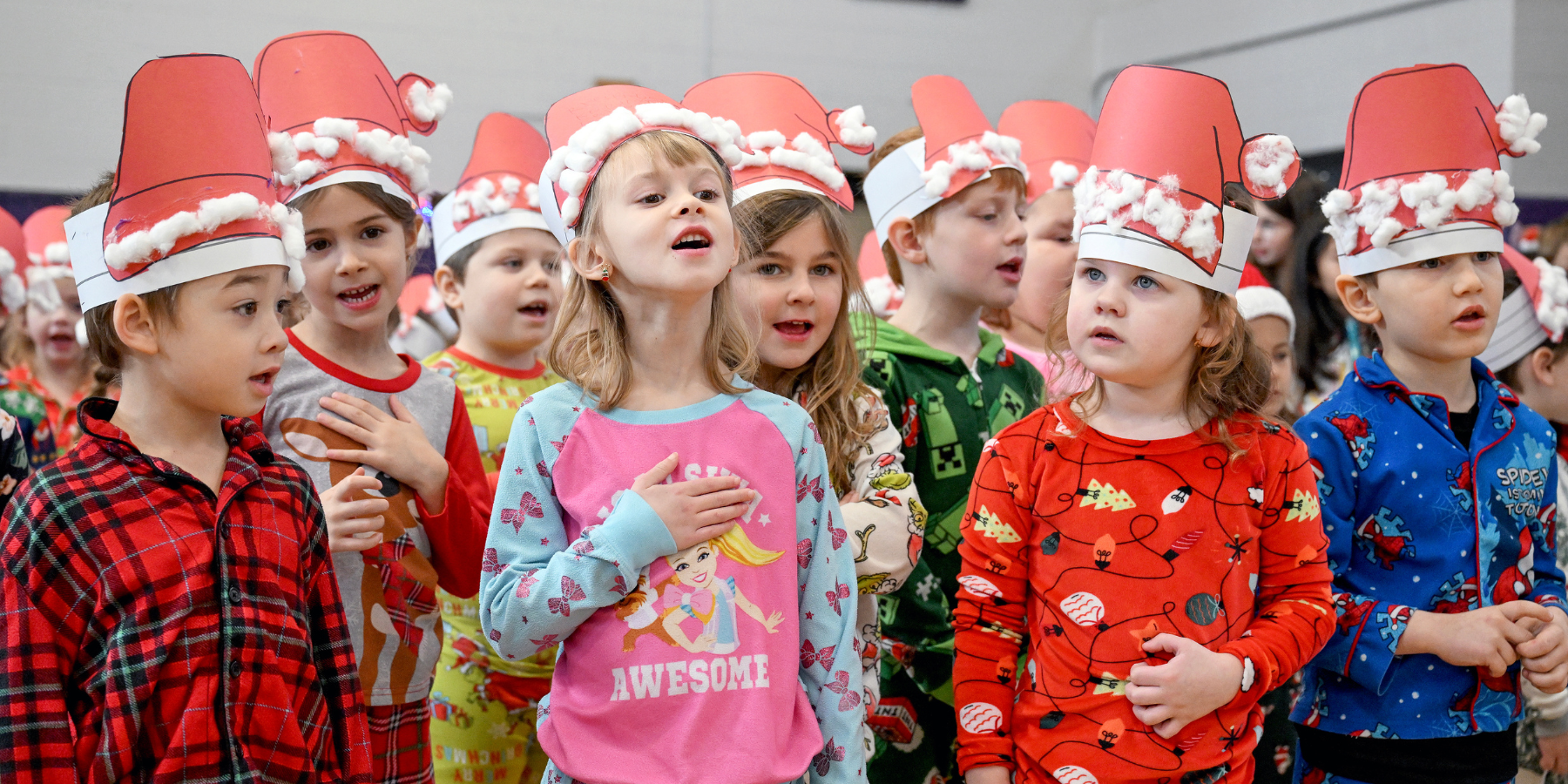 students wear handmade santa hats as they sing a song