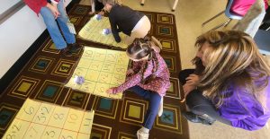 students sit on the floor as they participate in a coding activity