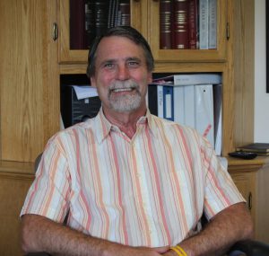 a man wearing a striped shirt sits at a desk