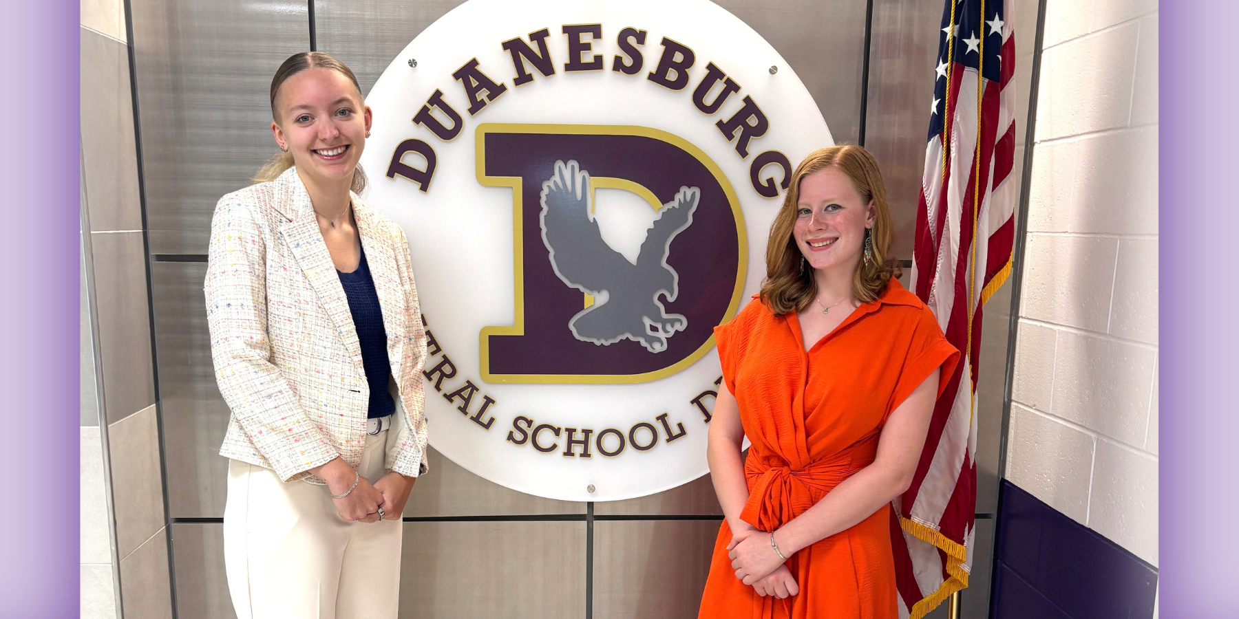 two young girls stand in front of their school logo