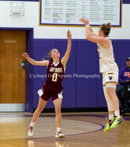 a girl wearing a white uniform shoots a basketball