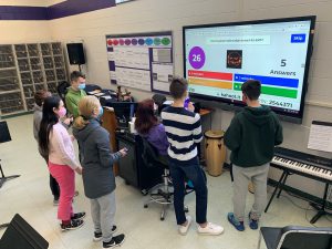 a team of students practice trivia questions on a large screen