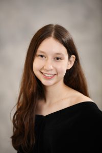 a girl with long dark hair poses for a senior photo