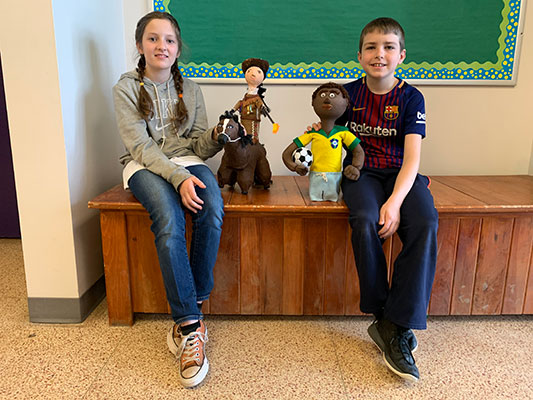 Female student holding Annie Oakley bottle person and male student holding Pele' bottle person