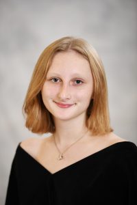 a girl with shoulder length blonde hair poses for a senior portrait