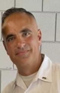 a man wearing a white shirt stands in front of a wall of white tile