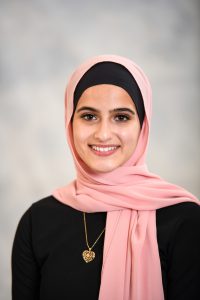 a girl wearing a pink hijab poses for a senior portrait
