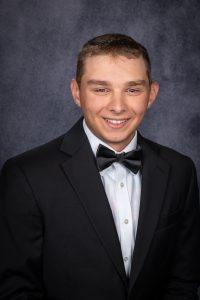 a young man in a tuxedo smiles at the camera