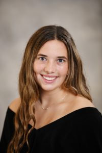 a girl with long brown hair poses for a senior portrait