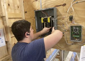 a young man with dark hair is shown working on an electrical panel