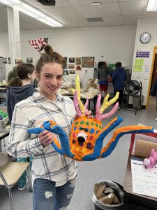 a student holds a paper mache art project