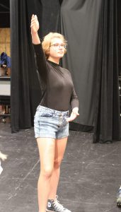 a teenaged actor stands on the stage and poses