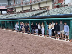 students stand inside a baseball dugout