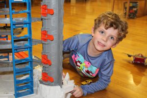 a young boy with curly hair plays with toy cars