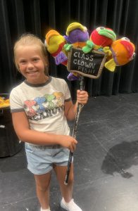 a youth actor holds up a prop of school fish while on stage