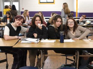 four young female students sit at a cafeteria table