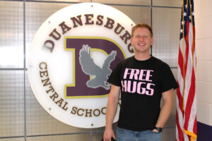 a man stands in front of a school logo