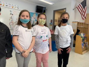 three young female elementary students pose in white t-shirts
