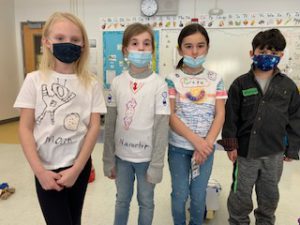 four students pose in a classroom