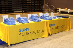 a table with a yellow table cloth is shown with blue t-shirts on top
