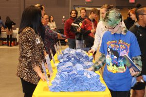 students walk past a table with a yellow table cloth and pick out t-shirts