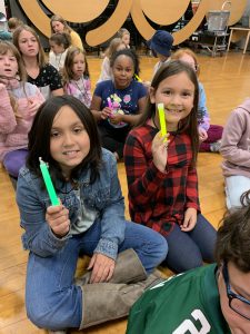 two students hold up glow sticks