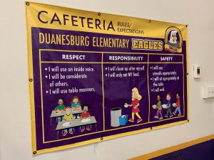 a purple and gold poster explains behavioral rules in the cafeteria