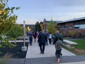 a group of people walk down a cement walkway at sunset