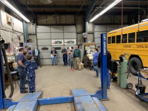a group of people tours a bus garage