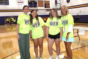 two young teenaged girls pose with two adult women in a gymnasium
