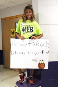 a young girl holds a handmade sign that reads "Ready to Rock"