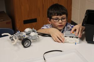 a young boy wearing glasses builds a robot