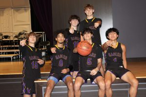 Six teenaged boys pose in basketball uniforms