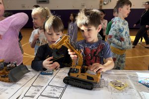 two young boys play with a toy crane