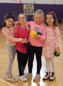 four young girls stand together in a gymnasium