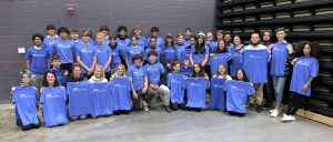 a group of students wear blue shirts and post together in a school.