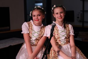 two girls wearing costumes pose behind a microphone