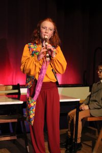a young girl plays the recorder on a theatrical stage
