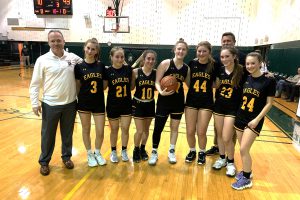 a girls basketball team poses together on the basketball court