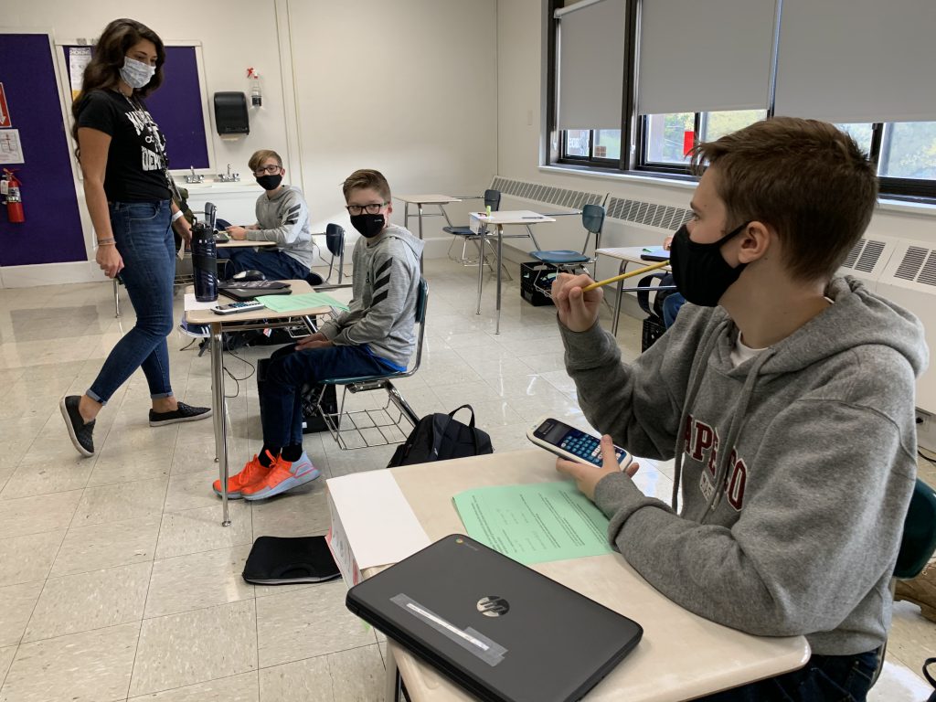 students and a teacher all wearing masks during a lesson in a school classroom