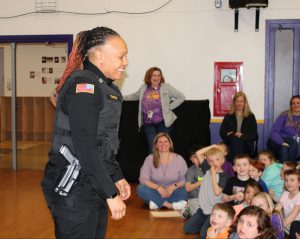 a female police officer smiles at a student assembly