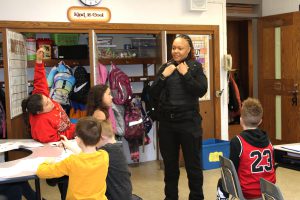 a police officer chats with elementary students in a classroom