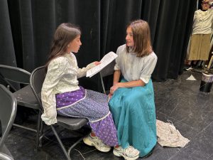 two young girls rehears play lines while on a stage